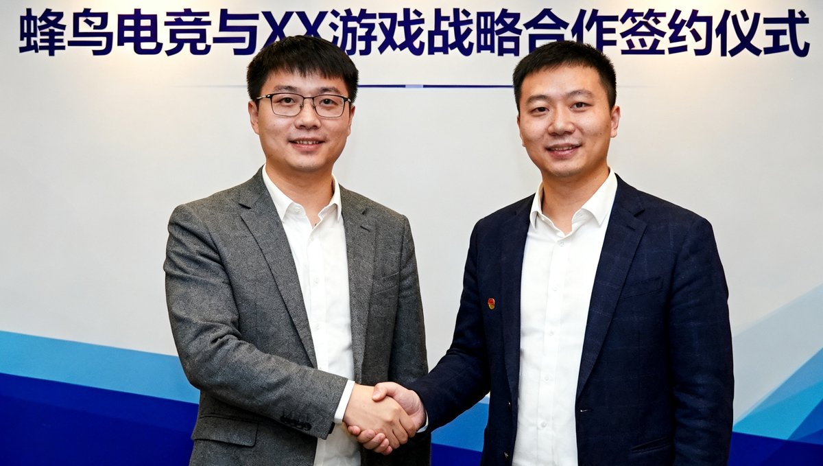 蜂鸟电竞与某知名游戏公司在签约仪式上双方代表握手合影，背景为合作主题背景板，气氛庄重而友好